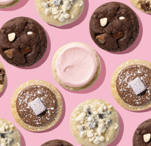 A range of flavors sold by Crumbl Cookies including Peanut Butter Munch, Pink Sugar, Blueberry Muffin, and Triple Chocolate Chip.